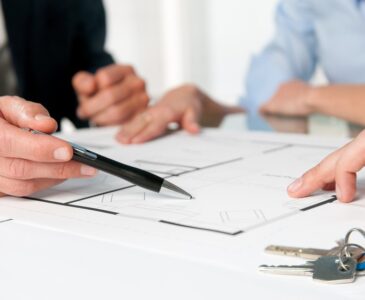 Closeup view of new home keys and house plan during a discussion with a real estate agent